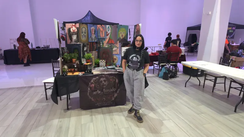 Salón de La Fundación Eventos en luz morada, con Sara Villa de pie en su stand entre los demás expositores