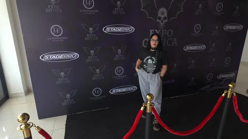 Sara Villa posando en el photowall de patrocinadores de la Expo Gótica, detrás de un cordón rojo