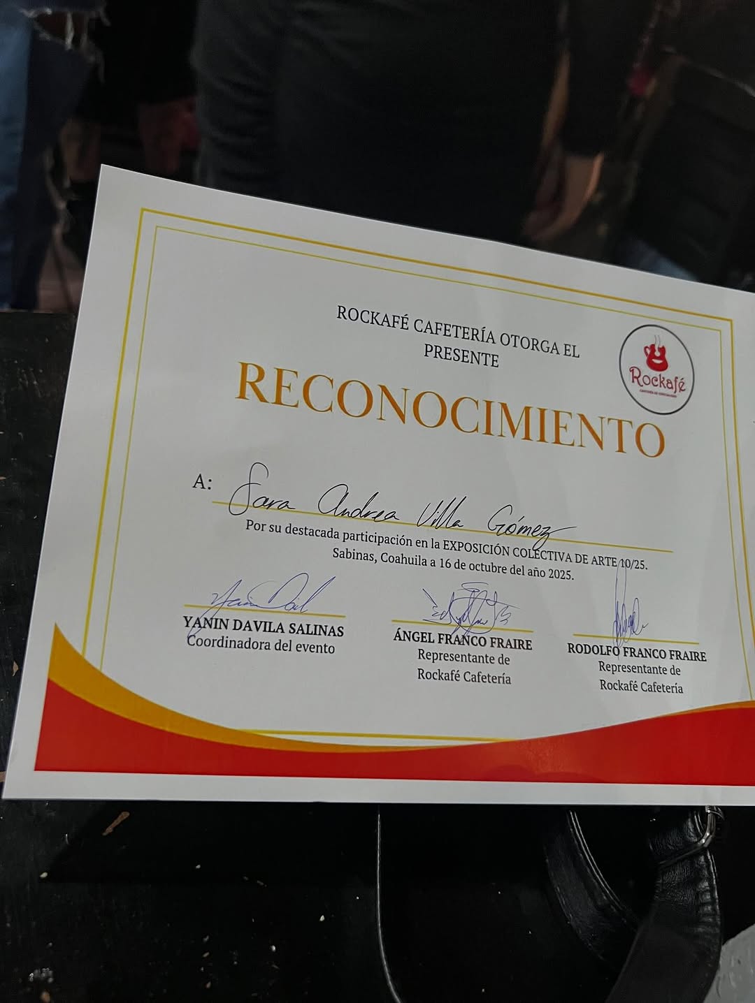 Reconocimiento del Rockafé Cafetería a Sara Andrea Villa Gómez por su participación en la Exposición colectiva de arte 10/25, Sabinas, 16 de octubre de 2025